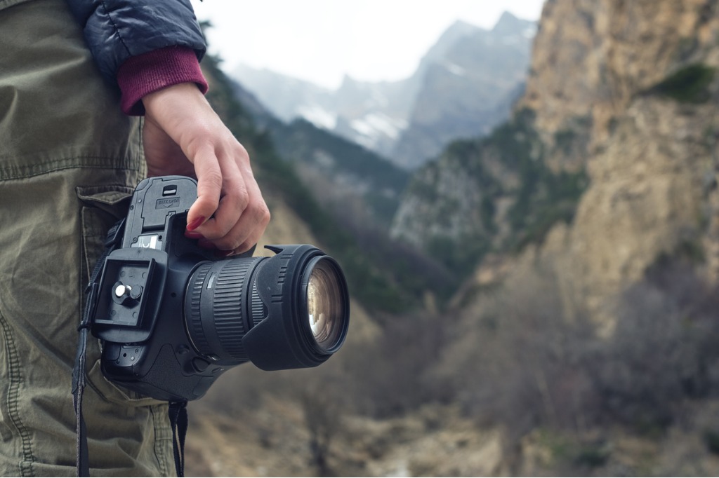 female hand holds a camera against a mountain landscape picture id866954210 image 