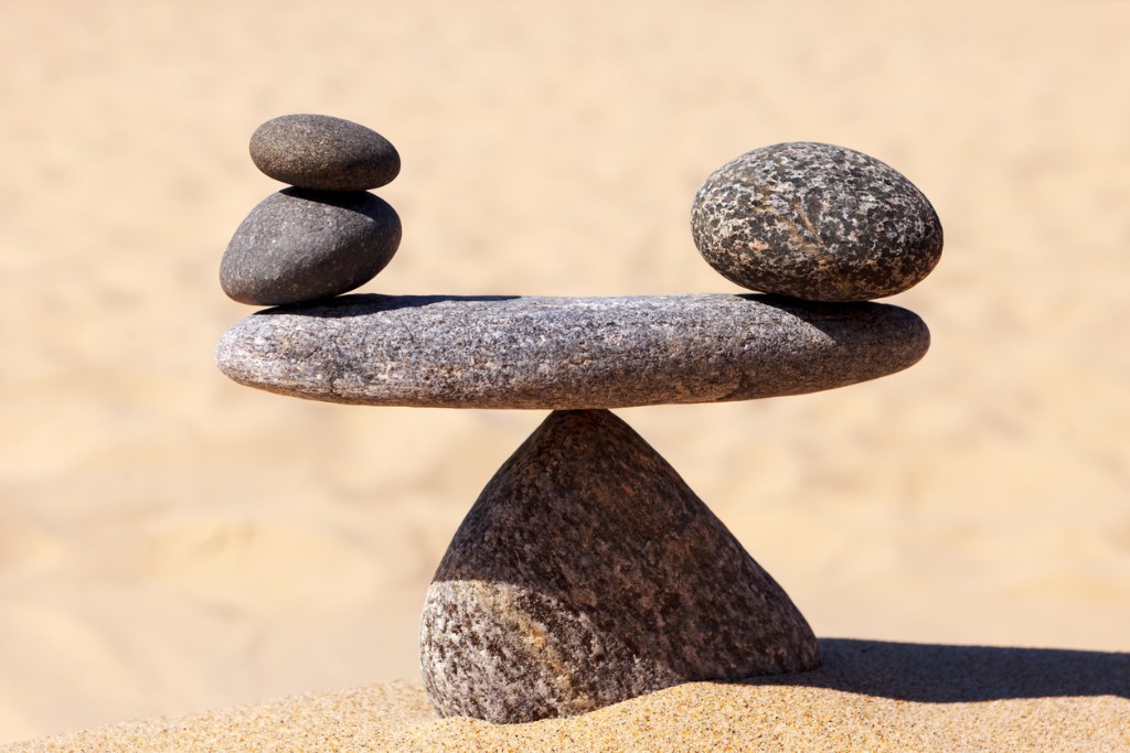  A rock formation on a beach with smooth round stones on top of each other and a large stone balancing them on a thin rock creating a balance.